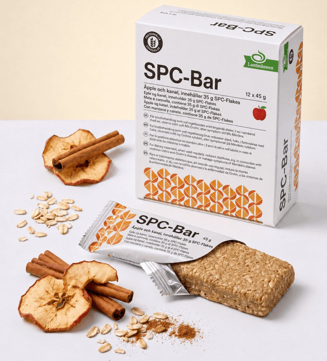 Boîte de SPC-Bar 12 x 45 g avec une barre ouverte, des tranches de pomme séchées, des bâtons de cannelle et des flocons d'avoine